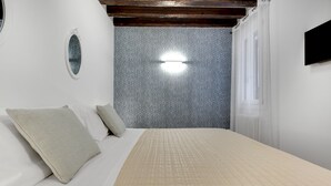 A bedroom with a bed, pillows, a wall-mounted light, and a patterned wallpaper. - Laguna Luxury 1 by Wonderful Italy (Venice)
