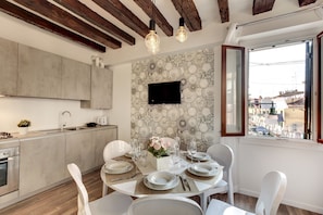 A modern kitchen with a dining area, a flat-screen TV mounted on the wall, and a view of the city through a window. - Laguna Luxury 1 by Wonderful Italy (Venice)