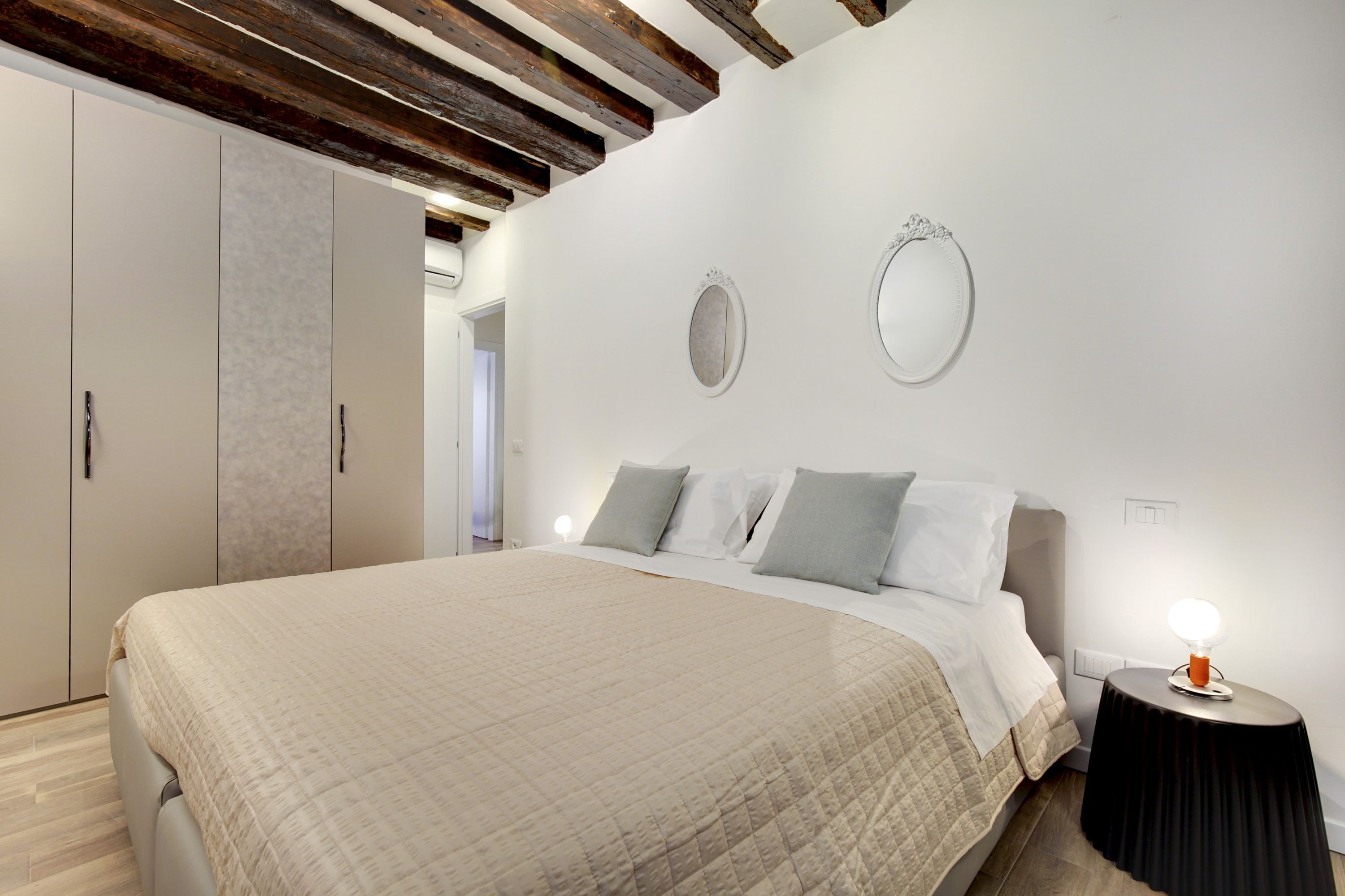 Ein Schlafzimmer mit einem Bett, Nachttischen, einem Kleiderschrank und einem Spiegel an der Wand.