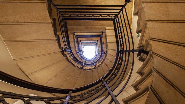 Un escalier en colimaçon qui offre une vue sur le ciel par le sommet.