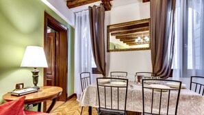Un coin repas avec une table dressée pour quatre personnes, une chaise rouge, une lampe et un miroir au mur.