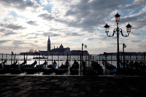 Gondolas docked at a pier with a historic building in the background. - Byron San Marco by Wonderful Italy (Venice)