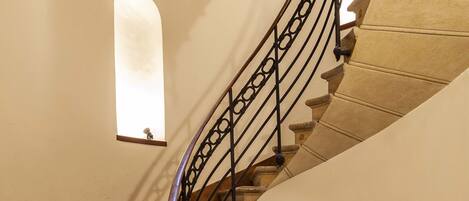 A spiral staircase with a wrought iron railing and a small window at the top.