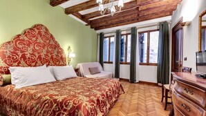 Une chambre à coucher avec un grand lit, une commode en bois, une chaise et un téléviseur.