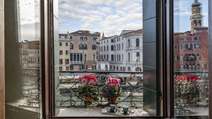 A view from a window with ornate iron railings, potted plants, and a tray with a cup and saucer. - Rialto Grand Canal - Locz (Venice)