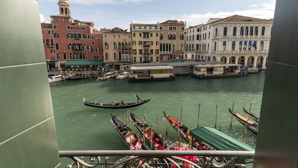 A canal with gondolas docked at the side, a historic building with a bell tower, and a bridge over the water. - Rialto Grand Canal - Locz (Venice)
