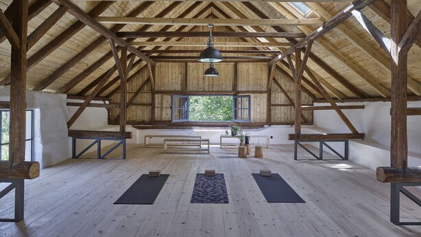 A spacious attic room with wooden beams, a slanted ceiling, and skylights. There are yoga mats on the floor and a bench in the center. - Wmm020 in Manet n With 7 Bedrooms and 8 Bathrooms (Manětín)