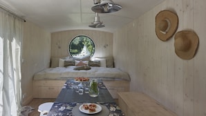 A cozy room with a bed, a round window, a table with a placemat, and two hats on the wall. - Wmm020 in Manet n With 7 Bedrooms and 8 Bathrooms (Manětín)