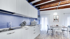 Une cuisine moderne avec des meubles blancs, une cuisinière à gaz et un four à micro-ondes. On y trouve également un coin repas avec une table et des chaises.