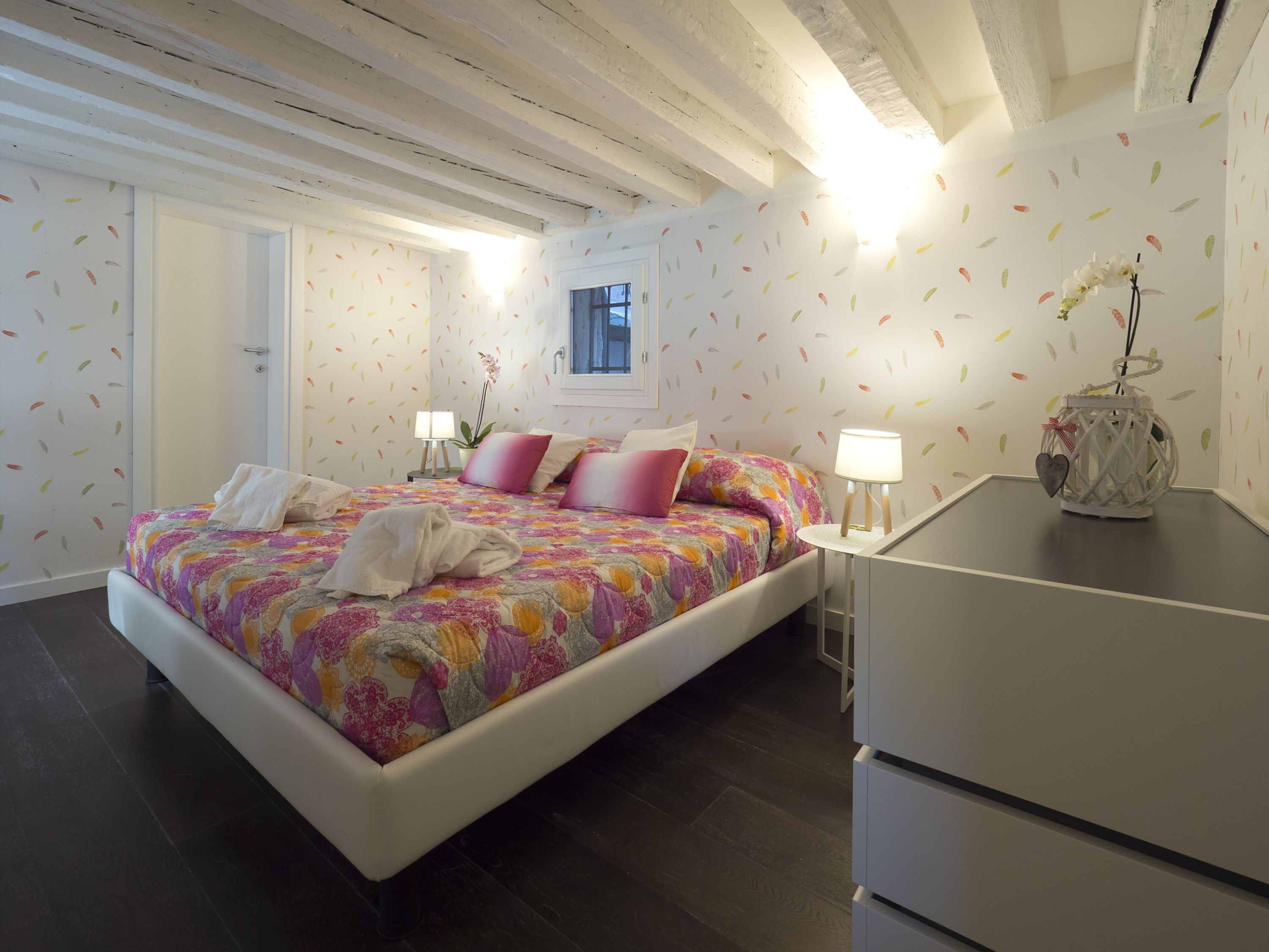 Een slaapkamer met een bed, bedlampjes, een raam en een decoratieve lantaarn.