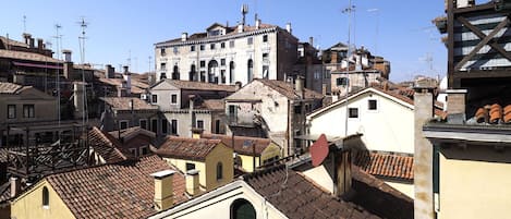 Un edificio storico con numerosi balconi e un tetto in tegole, circondato da altri edifici di stile architettonico simile.