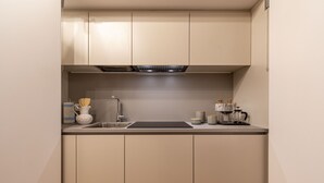 A compact kitchen with beige cabinets, a black countertop, a sink, a faucet, and various kitchen items including a coffee maker and jars. - Ca Della Commedia by Wonderful Italy (Venice)