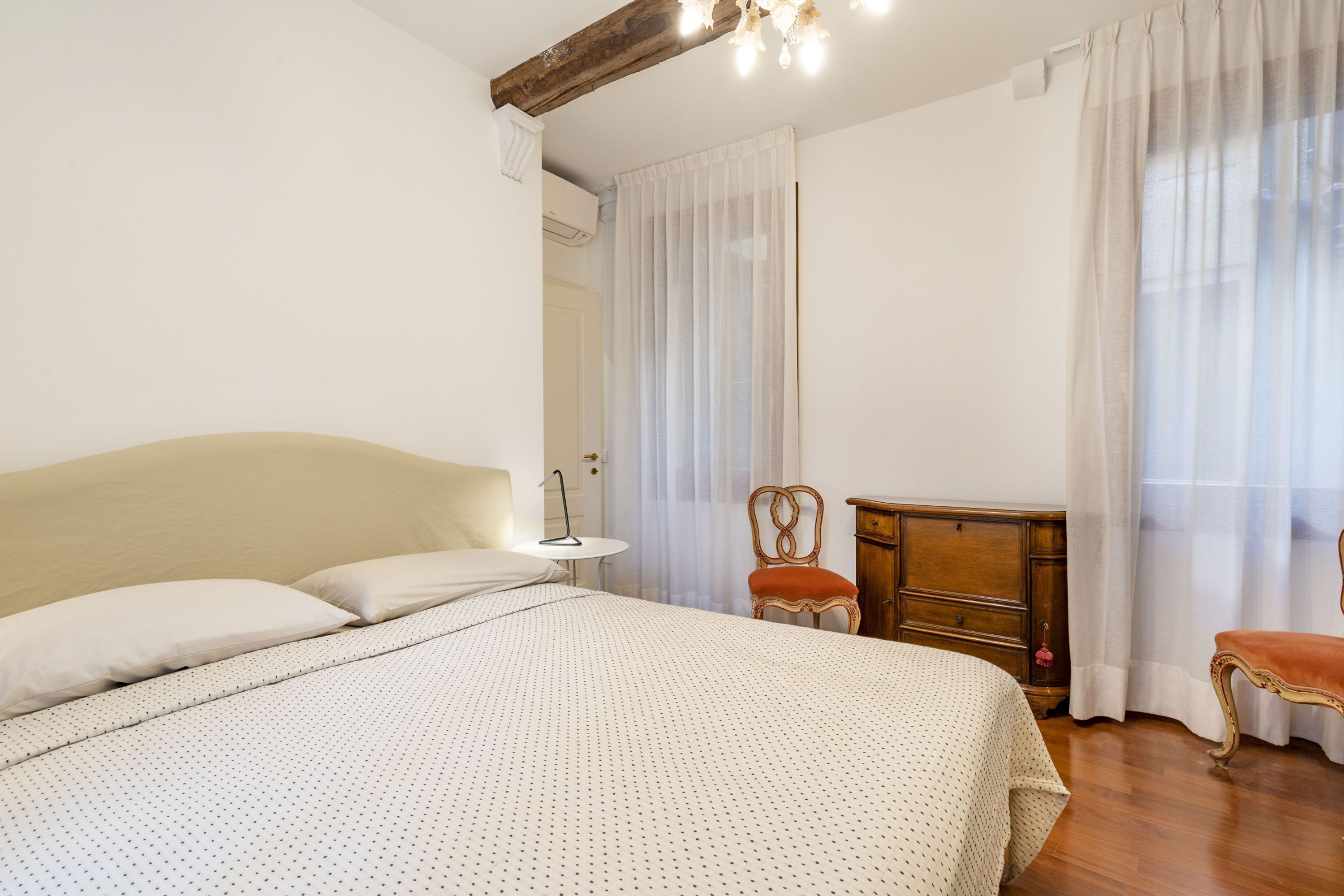 Un dormitorio con una cama grande, un aparador de madera, una silla y un banco.