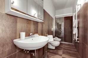Et moderne badeværelse med en stor vask, toilet, bidet og et bruseområde med glasvægge.