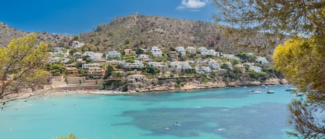 Une ville côtière avec des bâtiments construits sur une colline surplombant une baie aux eaux turquoise.