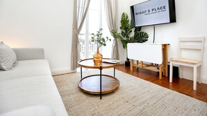 Ein modernes Wohnzimmer mit einer Couch, einem runden Couchtisch, einem an der Wand befestigten Fernseher und einer Pflanze.