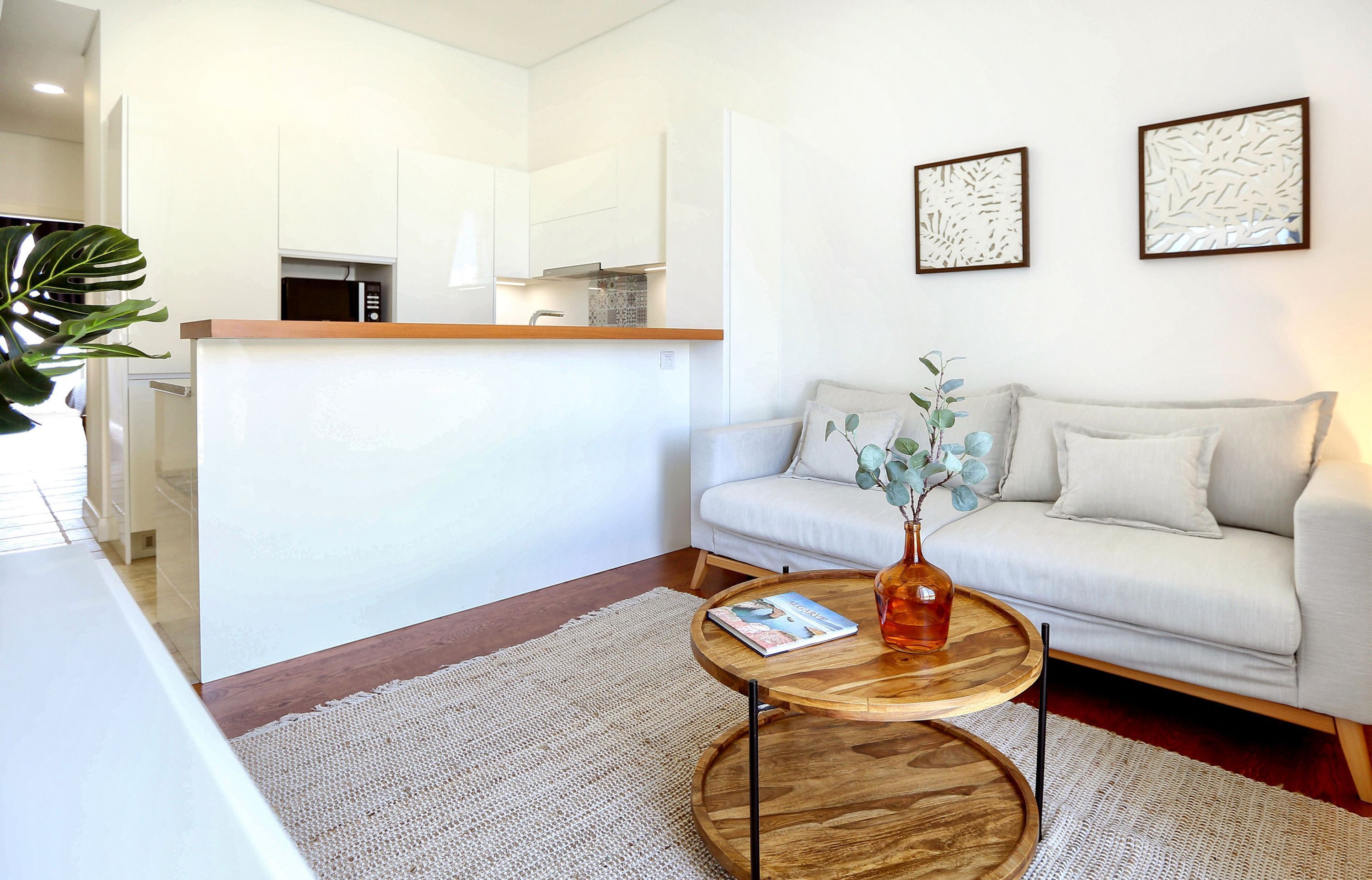 A modern living room with a sofa, a coffee table, and a kitchen area in the background.
