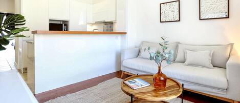 A modern living room with a sofa, a coffee table, and a kitchen area in the background.