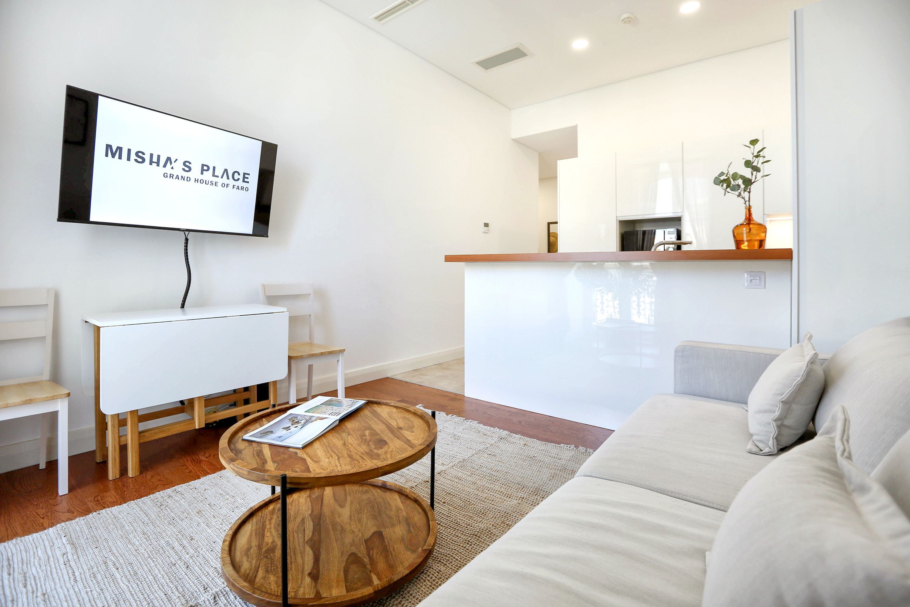 A modern living room with a sofa, a coffee table, and a TV mounted on the wall.