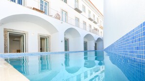 Ein Swimmingpool mit klarem, blauem Wasser, weißen Wänden und blauen Fliesenrändern.