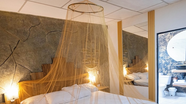 Un dormitorio con una cama grande, dosel y pared de piedra.