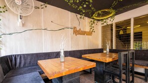 Un interior de restaurante con mesas de madera y asientos acolchados en negro.
