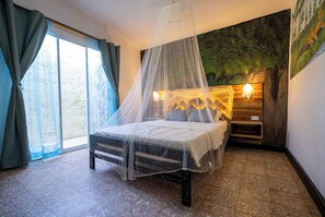 A bed with a canopy, a nightstand, a wall-mounted lamp, and a large window with curtains. - Ambos Mundos Hotel Boutique (Santa Marta)