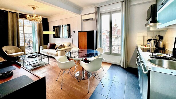 Een moderne woonkamer met een glazen salontafel, witte banken en een kroonluchter.
