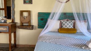 A bed with a canopy, a wooden nightstand, a wall-mounted shelf, and a decorative wall piece. - Habitación Lupe Gil. (San Francisco)