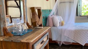 A rustic wooden bed with a white canopy, a wooden nightstand with glass jars, and a woven basket. - Habitación Lupe Gil. (San Francisco)