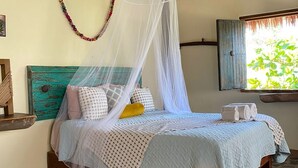 A bed with a canopy, a wooden headboard, and a window with a view of greenery. - Habitación Lupe Gil. (San Francisco)