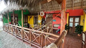 A thatched-roof structure with a wooden fence, a bench, and a door. - Habitación Lupe Gil. (San Francisco)