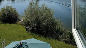 A view of a river with a boat, surrounded by greenery and a clear sky. - Peaceful Lakefront Escape w/ Sunset Views (South Cerney)