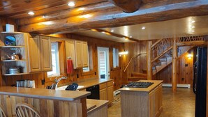A rustic kitchen with wooden cabinetry, a central island, and a staircase leading to another level. - Redpebble, a spacious upscale but classic vacation home on a crystal clear lake! (Land O' Lakes)