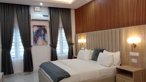 A bedroom with a large bed, wooden headboard, bedside lamps, and a nightstand.
