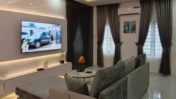 A modern living room with a flat-screen TV, a sofa, a coffee table, and a decorative vase.