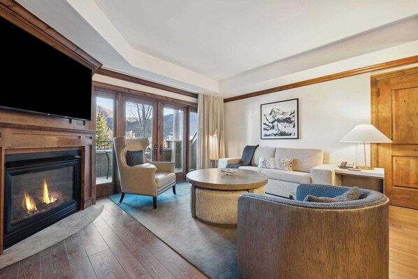 A modern living room with a fireplace, comfortable seating, and large windows offering a view of the outdoors.