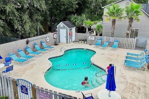 Ett privat poolområde med solstolar, ett litet förråd och en skylt med information om badvakten.