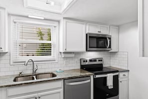 A kitchen with white cabinetry, a stainless steel sink, a microwave, an oven, and a dishwasher. - 3 Blocks to Beach - Sleeps 8 - 5 Bd - Pet Friendly (North Myrtle Beach)