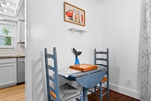 A dining area with a table set for two, featuring a blue chair with a whale-shaped backrest and a chessboard. - 3 Blocks to Beach - Sleeps 8 - 5 Bd - Pet Friendly (North Myrtle Beach)