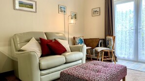 A living room with a sofa, a patterned ottoman, a lamp, and a chair. - A beautiful, cosy cottage in a peaceful setting with 15% off ferry (Shanklin)