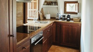 A kitchen with wooden cabinets, a built-in oven, a sink, and a window with a view. - Can Escu - Villa in the Heart of the Tramuntana Mountains (Sóller)