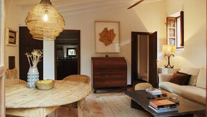 A dining area with a round wooden table, a wicker pendant light, and a vase with dried flowers. - Can Escu - Villa in the Heart of the Tramuntana Mountains (Sóller)