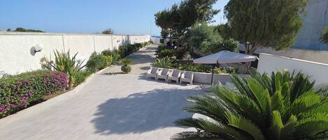 A paved outdoor area with seating and a view of the sea.
