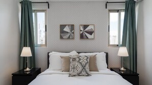 A hotel room with a bed, two nightstands, a window with curtains, and two wall art pieces. - RELAXING*1BR*Pool |Gym* Rooftop *yellowkey* (Santo Domingo)