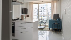 A modern kitchen with a stove, cabinets, and a dining area with a table and chairs. - RELAXING*1BR*Pool |Gym* Rooftop *yellowkey* (Santo Domingo)