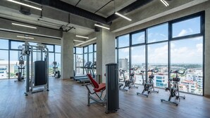 A spacious gym with large windows, various exercise equipment, and a city view. - RELAXING*1BR*Pool |Gym* Rooftop *yellowkey* (Santo Domingo)