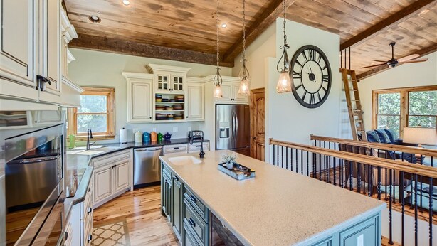 A spacious kitchen with a large island, wooden ceiling, and a clock on the wall. - Rocky Mountain Retreat - Hot Tub and EPIC views! (Rollinsville)