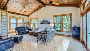 A spacious living room with a high ceiling, wooden beams, and large windows offering a view of the outdoors. - Rocky Mountain Retreat - Hot Tub and EPIC views! (Rollinsville)