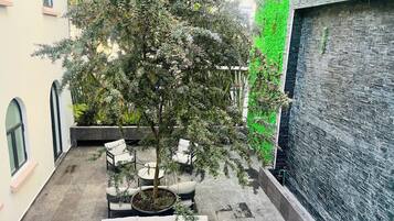 Ein Innenhof mit Baum, Sitzgelegenheiten im Freien und einer grünen Wand.